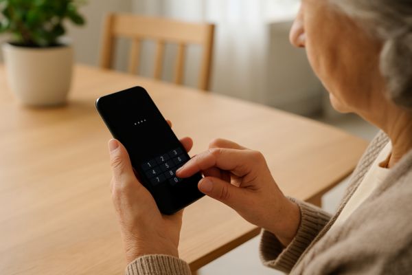 Pessoa madura digitando senha no celular com atenção e cuidado